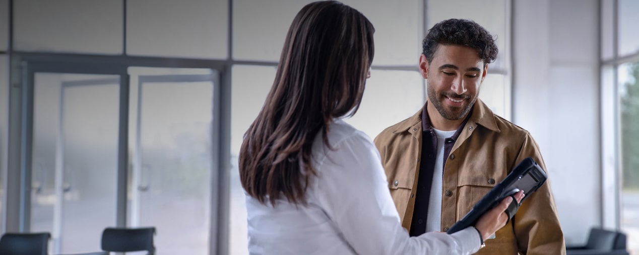 Escena en concesionario con personas revisando información en una tablet y encabezado “Dudas y Preguntas”, sección de consultas sobre suscripción digital Chevrolet