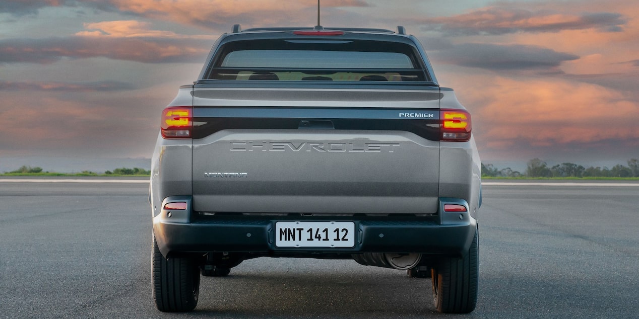 Vista trasera de Chevrolet Montana gris con luces encendidas, destacando los sistemas de alerta de frenado de emergencia y frenos ABS en un entorno al aire libre al atardecer.