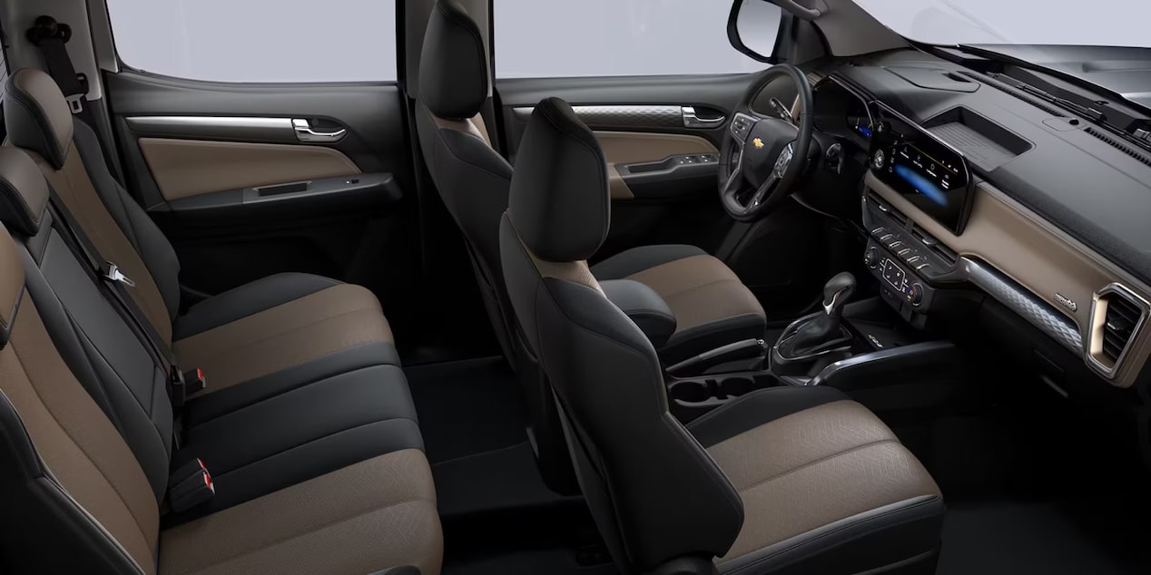 Interior de Chevrolet S10 con cabina doble, asientos tapizados, panel digital y amplio espacio para los pasajeros, destacando la comodidad durante la conducción.
