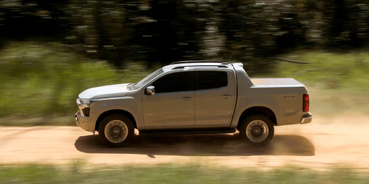 Chevrolet S10 blanca en movimiento sobre un camino de tierra, destacando la transmisión automática de 8 velocidades y su desempeño en diferentes terrenos.