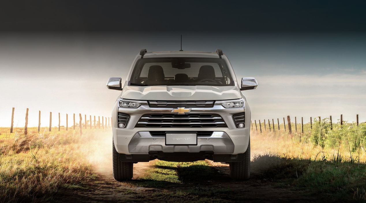 Chevrolet S10 4x2 WT blanca vista de frente sobre un camino rural, rodeada de vegetación y cercos. Imagen promocional de Plan Chevrolet con información de financiación y cuotas.