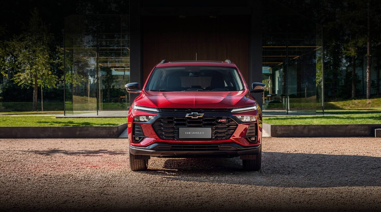 Chevrolet Tracker LT AT Turbo roja vista de frente, estacionada frente a una vivienda moderna. Imagen promocional de Plan Chevrolet con financiación de hasta 80% en 120 cuotas y seguro bonificado al 50% durante los primeros 3 meses.