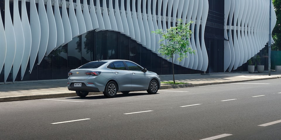 Vista lateral trasera del Chevrolet Onix Plus estacionado en área urbana