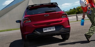 Vista trasera del Chevrolet Onix 2026 color rojo Jinx estacionado en área urbana
