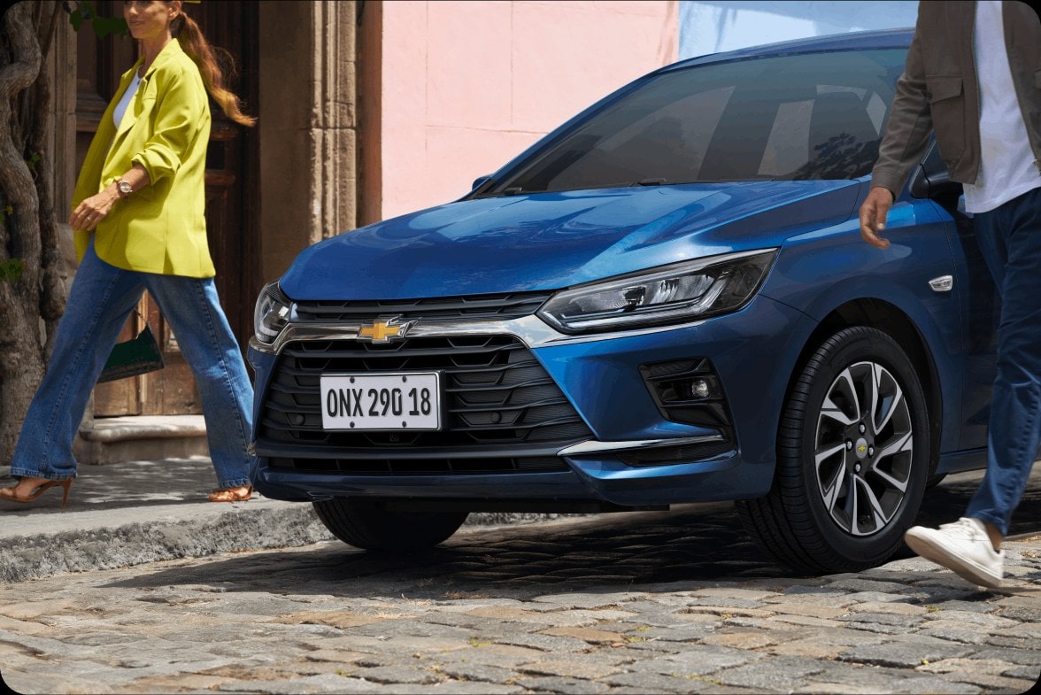 Vista frontal del nuevo auto Chevrolet Onix Hatchback 2027 color azul realizando maniobras en la ciudad, ilustrando la funcionalidad del sistema de estacionamiento Easy Park en Argentina.