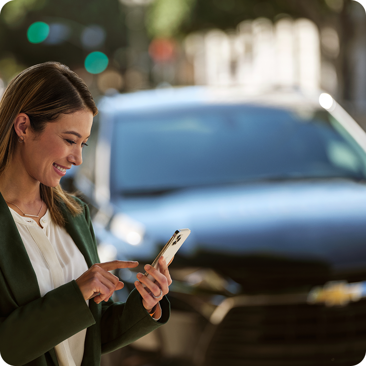 Propietaria utilizando la aplicación móvil myChevrolet en su smartphone junto a su vehículo, teniendo todo el control y servicios al alcance de sus manos en Argentina.