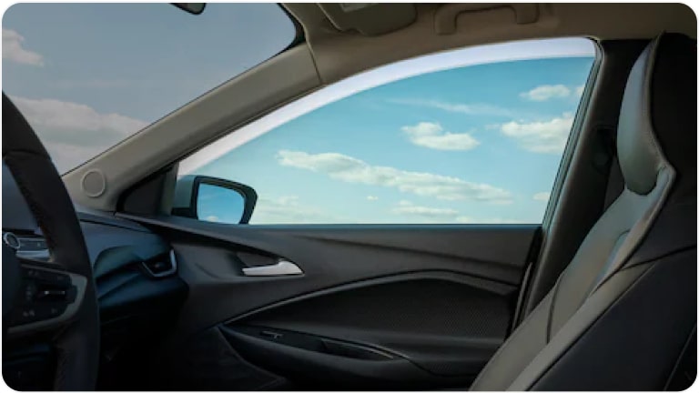 Vista interior de una de las ventanas delanteras de un Chevrolet Onix Plus, mostrando el rollo de película solar.