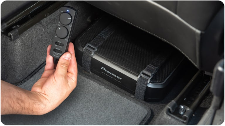 Plano en detalle de la mano de una persona sosteniendo el controlador de volúmen y ganancia de los parlantes Pioneer.