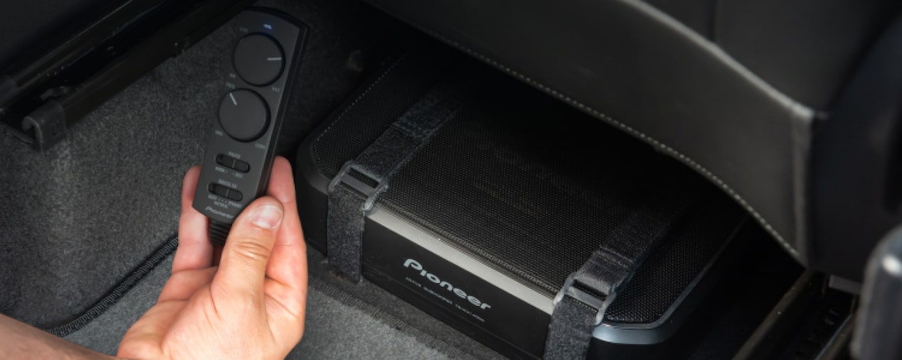 Plano en detalle de la mano de una persona sosteniendo el controlador de volúmen y ganancia de los parlantes Pioneer.