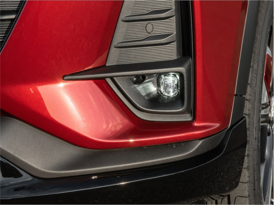 Primer plano del frente de un Chevrolet Onix Plus, enfocando el faro derecho integrado en un marco negro con detalles plásticos texturados.