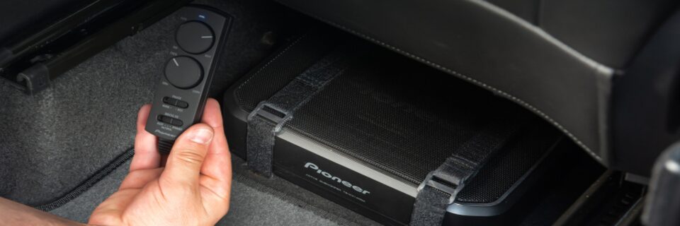 Plano en detalle de la mano de una persona sosteniendo el controlador de volúmen y ganancia de los parlantes Pioneer.