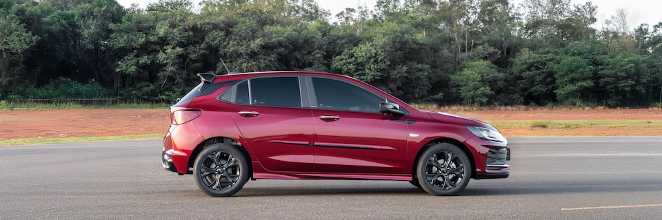 Lateral del Chevrolet Onix estacionado con vegetación de fondo.