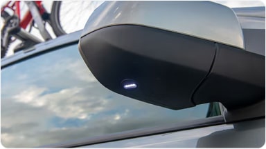 Detalle de las luces de bienvenida con iluminación LED integradas en los espejos retrovisores externos, aportando elegancia al ingresar a la nueva Chevrolet Spin en Argentina.