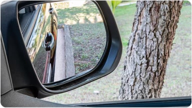 Vista desde el espejo retrovisor ajustado hacia abajo gracias al sistema Tilt Down, una tecnología avanzada para facilitar las maniobras de estacionamiento en la nueva Chevrolet Spin en Argentina.