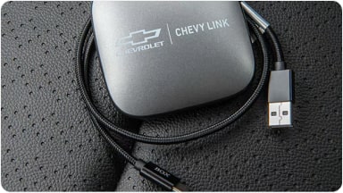 Detalle del accesorio Chevy Link junto a su cable de conexión, un módulo de entretenimiento que suma avanzadas opciones de conectividad a la nueva Chevrolet Spin en Argentina.