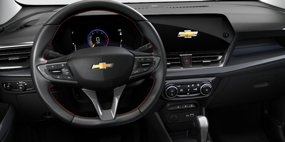  Interior de la Chevrolet Spin 2027 con vista del volante multifunción con costura roja, tablero digital de 8 pulgadas y pantalla táctil Chevrolet MyLink de 11 pulgadas con conectividad Wi-Fi, OnStar y cargador inalámbrico en Argentina.