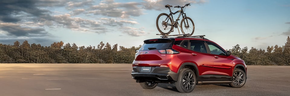 Chevrolet Tracker con una bicicleta montada en el soporte para el techo con vegetación de fondo.