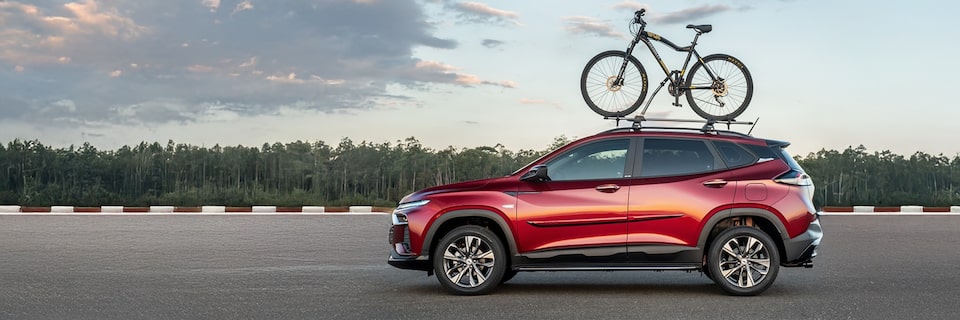 Vista lateral de la Chevrolet Tracker con una bicicleta montada en el soporte para el techo con vegetación de fondo.