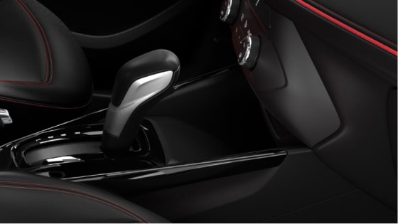  Detalle de la consola central de Chevrolet Tracker, con cargador inalámbrico para smartphones, palanca de cambios automática y terminaciones oscuras.