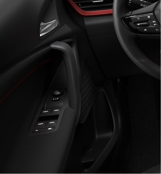 Detalle del interior de Chevrolet Tracker, con controles eléctricos de las ventanillas, apoyabrazos y terminaciones oscuras en la puerta del conductor.