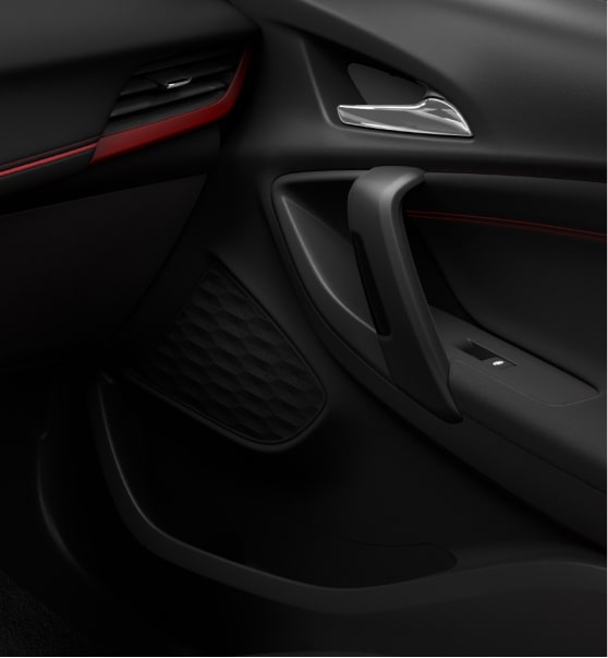 Detalle de panel interior de la puerta de Chevrolet Tracker, con manija de apertura, parlante integrado, espacio de almacenamiento y terminaciones oscuras con detalles rojos.