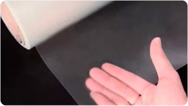 Vista de un rollo de película protectora para techo en acabado transparente mate, mostrando una mano detrás para destacar su textura, accesorio para la SUV Chevrolet Trailblazer en Argentina.