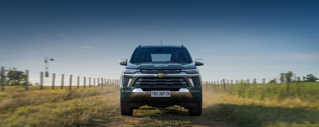 Vista frontal de la potente SUV Chevrolet Trailblazer color verde oscuro conduciendo por un camino rural, sección de accesorios originales en Argentina