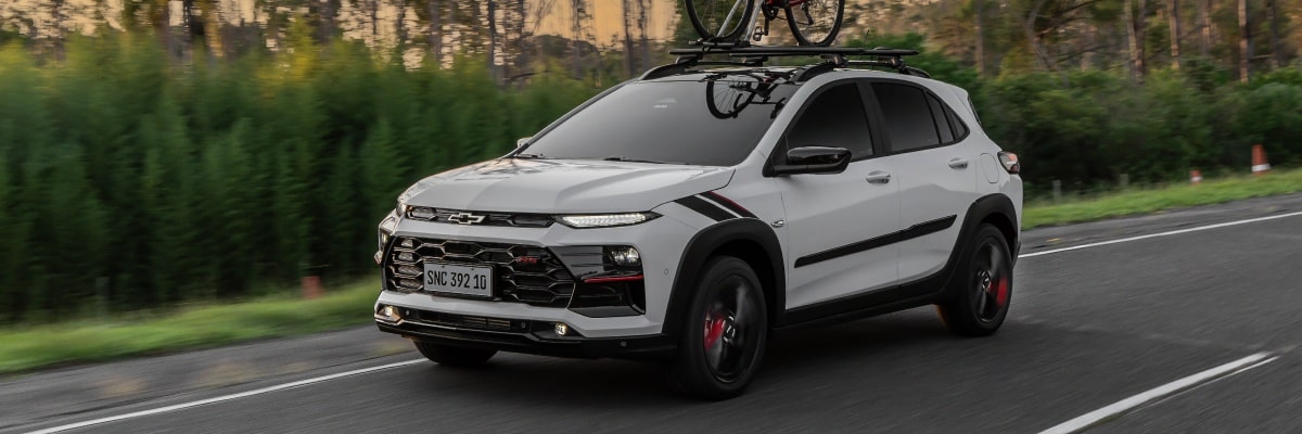 Chevrolet Sonic circulando por una ruta equipado con un porta bicicleta con vegetación de fondo.