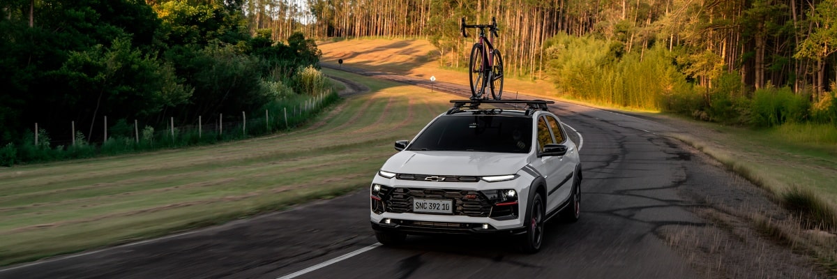 Vista superior del Chevrolet Sonic circulando por una ruta equipado con un porta bicicleta con vegetación de fondo.