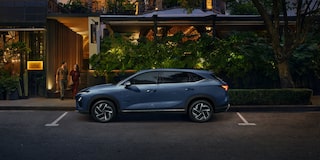 Vista lateral de la Chevrolet Captiva PHEV estacionada en la puerta de un restaurante, mientras un hombre y una mujer salen por la puerta del local.