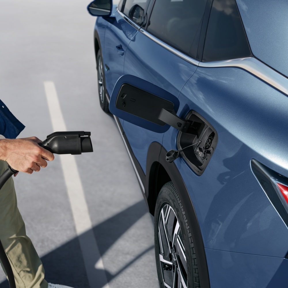 Imagen de la mano de un hombre mientras sotiene un cargador eléctico, a punto de cargar la Chevrolet Captiva EV.