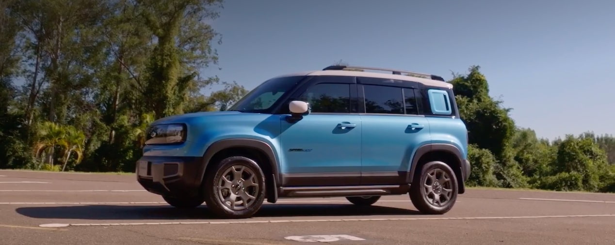 Vista lateral del Chevrolet Spark estacionado con vegetación de fondo.
