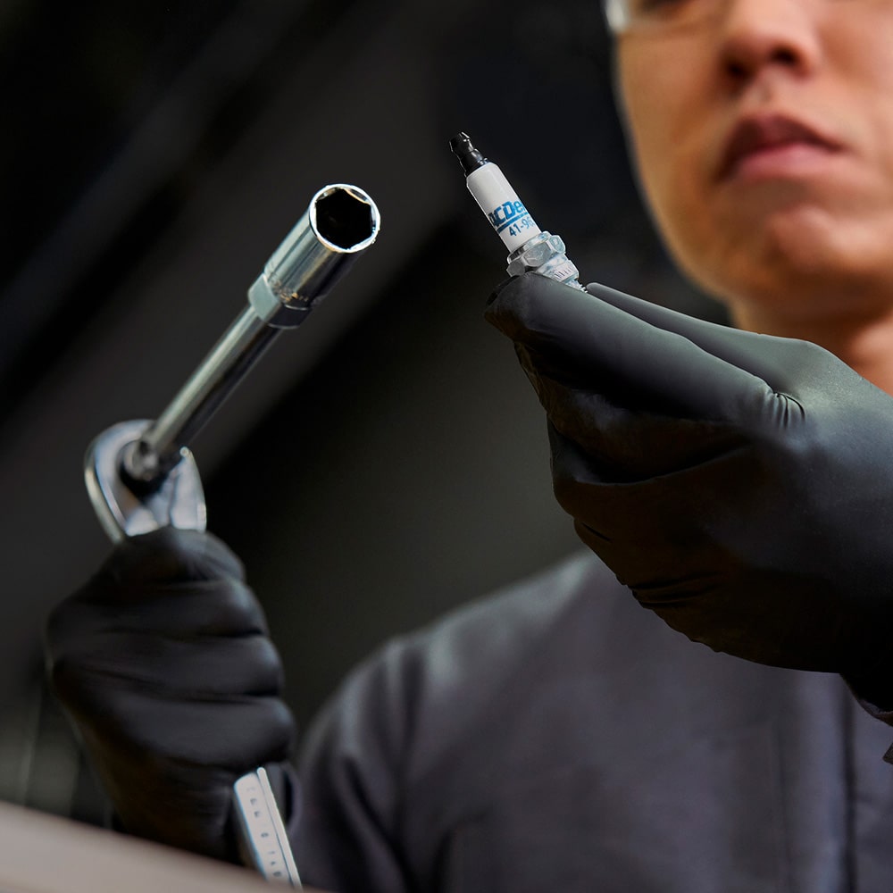 Técnico Chevrolet realizando mantenimiento con cambio de bujía para mejor rendimiento del motor