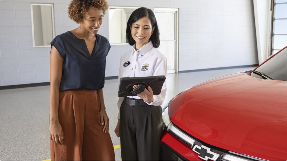 Imagen de una mujer siendo asesorada por una vendedora de una cocesionaria Chevrolet.
