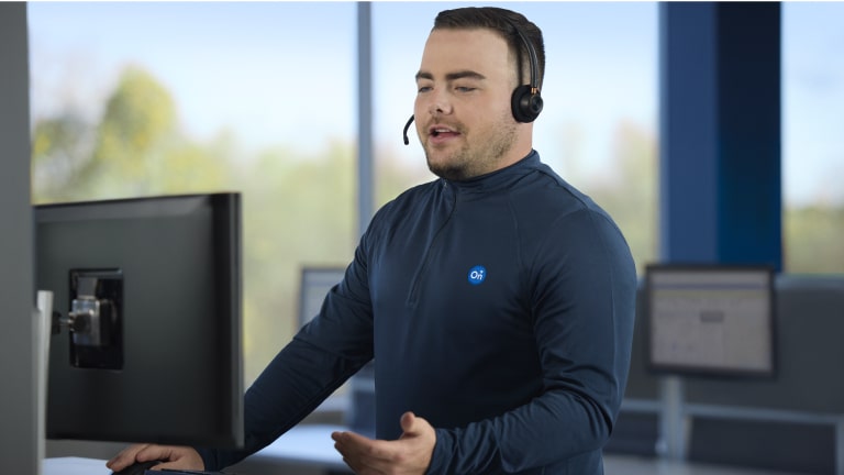 Imagen de un asesor del call center Chevrolet hablando por el micrófono de sus cascos frente a una computadora. 