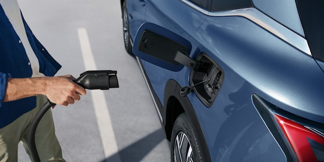 Imagen de la mano de un hombre mientras sotiene un cargador eléctico, a punto de cargar la Chevrolet Captiva EV.