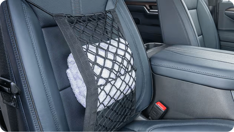 Imagen de la red de conveniencia para asiento instalada en el asiento del pasajero de la nueva Chevrolet Silverado, sujetando un almohadón blanco.