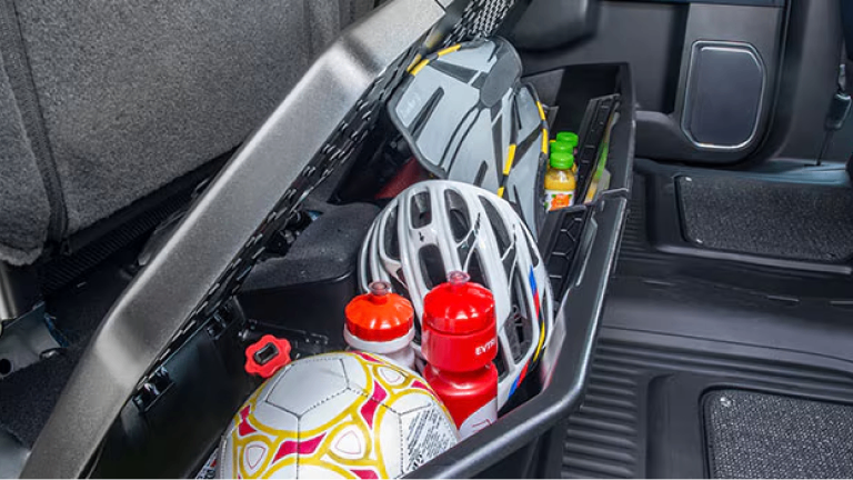 Imagen de la caja organizadora para debajo del asiento, cargada con articulos deportivos y botellas. 