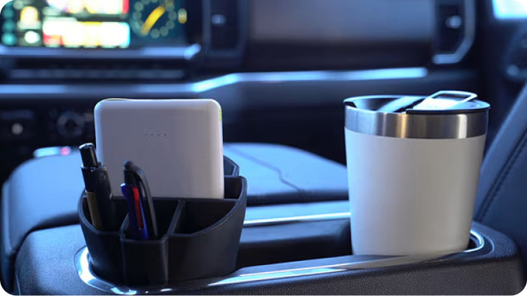 Imagen del organizador interno de portavasos, cargado con un vaso término, lapiceras y un celular. 