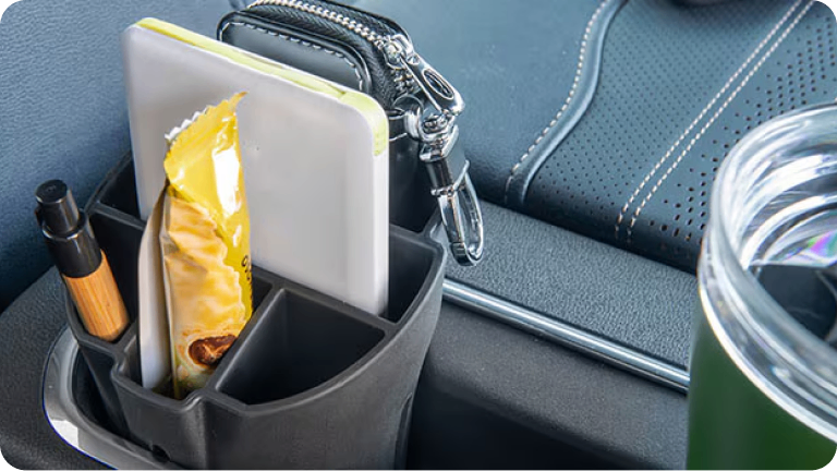 Imagen del organizador interno de portavasos, cargado con un monedero, una golosina y una lapicera.