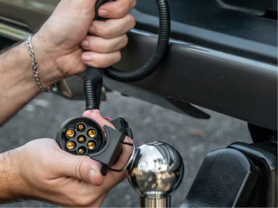 Imagen que muestra las manos de un hombre instalando el accesorio de enganche de remolque en la parte trasera de la nueva Chevrolet Silverado.
