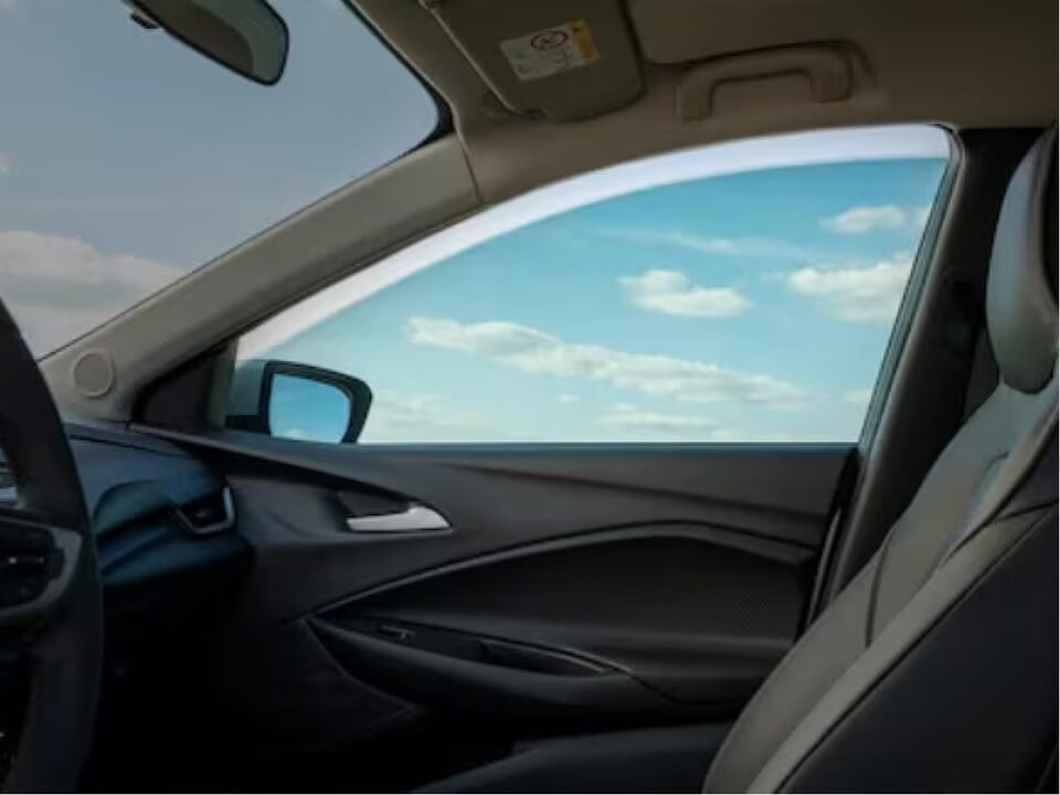 Imagen que muestra el interior del vehículo, destacando el accesorio de rollo de película para vidrio instalado en la ventanilla del pasajero.