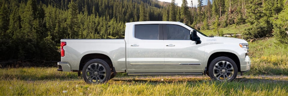 Imagen lateral de la nueva pick-up Chevrolet Silverado en medio de un campo con montañas al fondo.