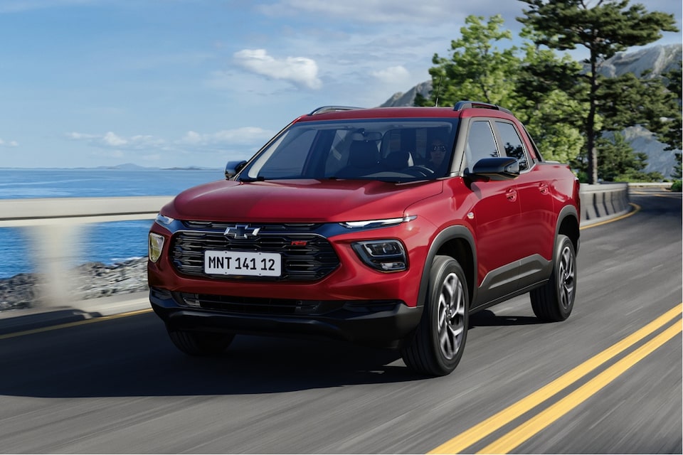 Chevrolet Montana en color Rojo Jinx circulando por una ruta con vegetación de fondo.