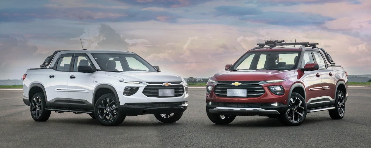 Vista frontal de dos Chevrolet Montana estacionadas con vegetación de fondo.