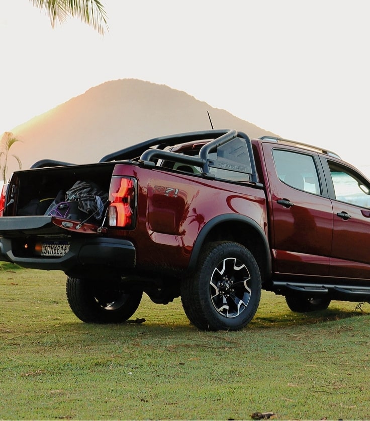 Chevrolet S10 Z71 color Rojo Jinx en espacio verde destacando barras deportivas extendidas.
