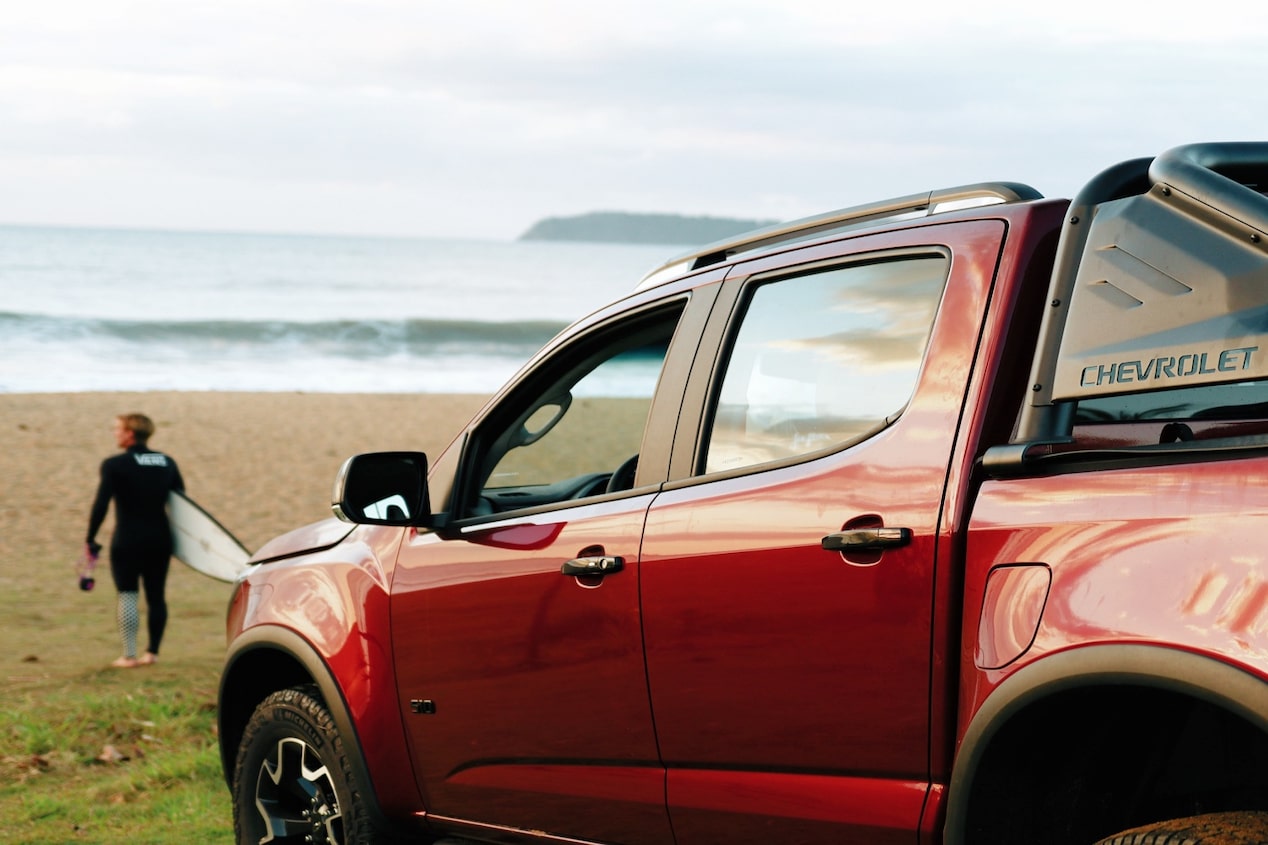 Chevrolet S10 2027 color rojo estacionada en la playa con un surfista al fondo en Argentina