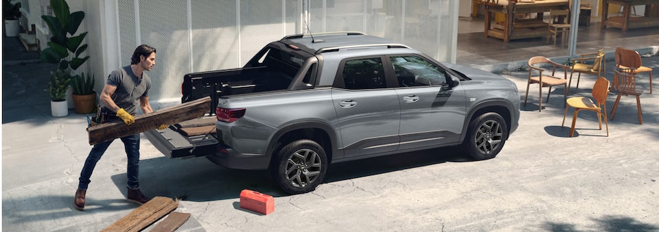 Vista lateral de la Chevrolet Montana con un hombre cargando maderas en la caja Multi-Flex con capacidad de 874 litros.