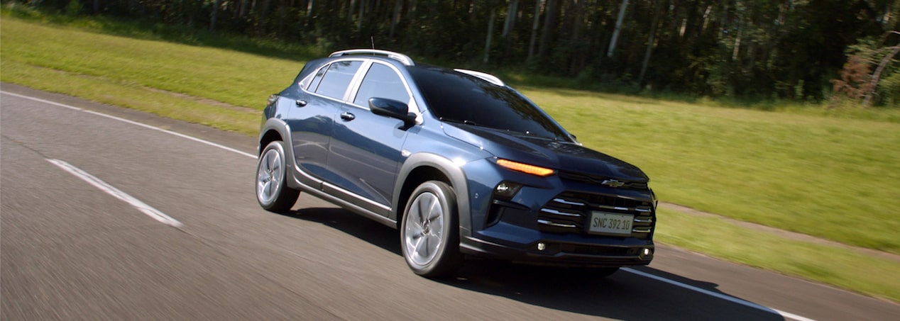 Chevrolet Sonic circulando por una ruta con vegetación de fondo.