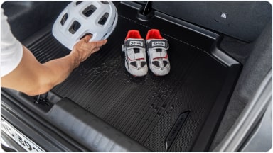 Alfombra de Baúl tipo Bandeja con Logo para el Chevrolet Sonic guardando un casco y zapatillas de ciclista.
